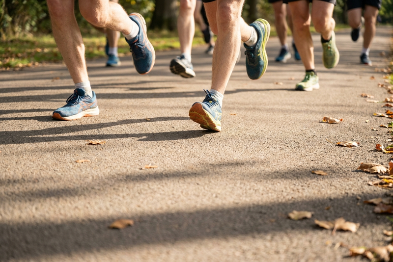 Anonymous group of charity runners in motion on a sunlit path: a generic image evoking a kidney charity fundraiser.
