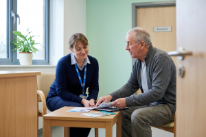 Kidney transplant support: a renal nurse and patient talking together in a bright NHS clinic